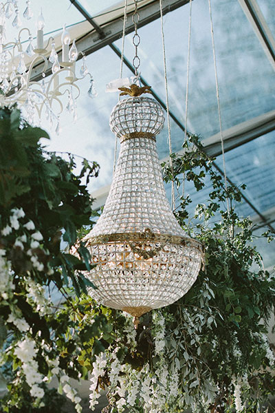 Stunning 90cm Empire chandelier in an outdoor clear marquee surrounded by greenery 