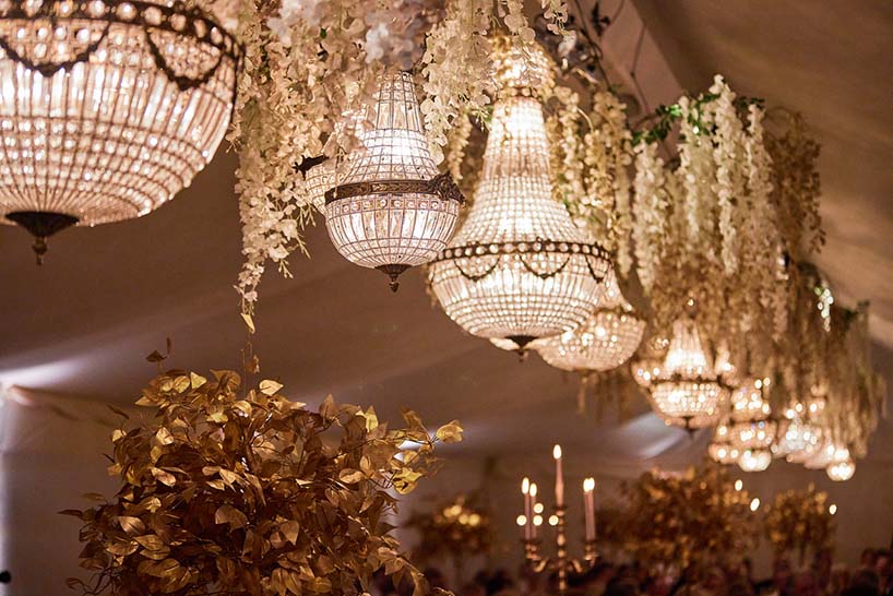 Wedding table with chandeliers hung above entwined with wisteria flowers