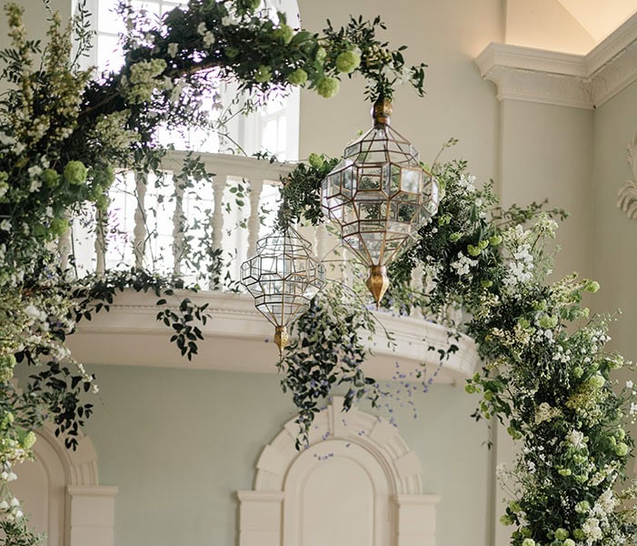 Detail of Gold and Glass Moorish Lanterns hung on arches covered in foliage