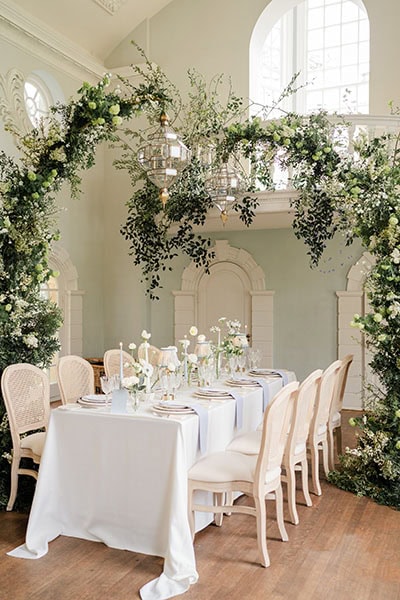 Gold and Glass Lanterns hung on arch covered in foliage for bridal photoshoot